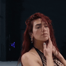 a woman with red hair is wearing a fishnet top