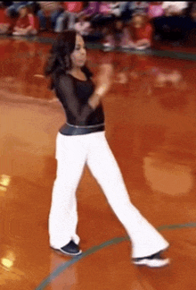 a woman in white pants is dancing on a basketball court .