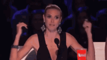 a woman is sitting in front of a microphone with her fist in the air .