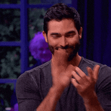 a man with a beard is clapping his hands and smiling .