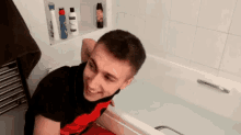 a man is sitting in a bathtub with a towel around his neck .