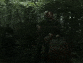 a man riding a horse in the woods with another man behind him