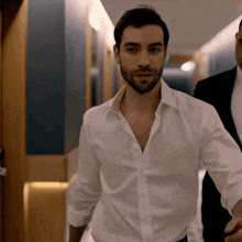 a man in a white shirt walking down a hallway