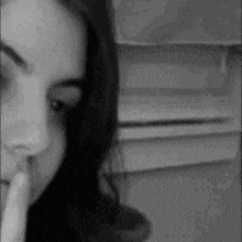 a black and white photo of a woman with her finger to her mouth .