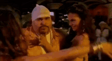 a man with a bandana on his head is dancing with two women .