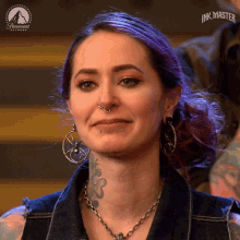 a woman with purple hair and earrings is on a paramount network ink master show