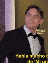 a man in a suit and bow tie is smiling in front of a sign that says miyake d' issey