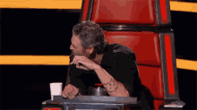 a man is sitting in a chair with his hand on his chin