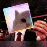 a man in a suit and tie is holding a rainbow colored cube with a picture of a cat on it