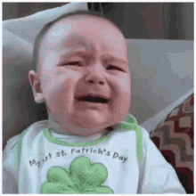 a baby wearing a bib that says my 1st st. patrick 's day cries