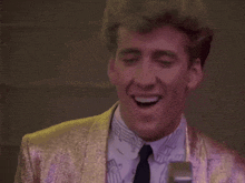 a man wearing a gold jacket and tie is making a funny face
