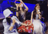 a woman singing into a microphone while another woman drinks from a cup