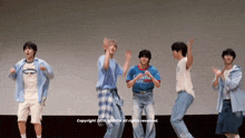 a group of young men are dancing on a stage in front of a sign that says copyright 2021 march all rights reserved .