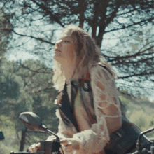 a woman sitting on a motorcycle looking up