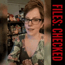 a woman wearing glasses is standing in front of a shelf of stuffed animals and a sign that says files checked