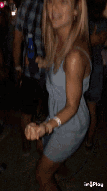 a woman in a blue dress is dancing with a man in a plaid shirt in the background