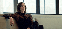 a woman is sitting on a couch with her arm resting on the arm of the couch