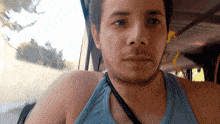 a man wearing a blue tank top is looking out a window