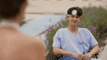 a man in a wheelchair with a bandage on his head talks to another man .