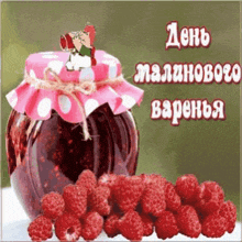 a jar of jam sits on a table next to raspberries .