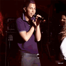 a man with purple hair is singing into a microphone while a woman looks on