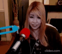 a woman is sitting in front of a microphone with a clipeo.com watermark on the bottom