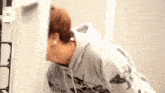 a woman in a hoodie is standing in front of a refrigerator and looking at it .