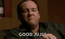 a man is sitting on a couch making a face and saying good juju !