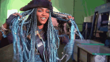 a woman with blue braids and a pirate hat is smiling