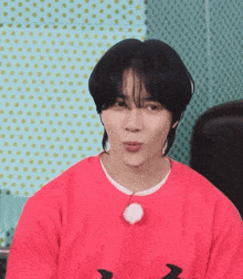 a young man wearing a red sweater is making a funny face