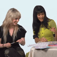 two women are sitting at a table and one of them is wearing a green shirt that says " i love you "