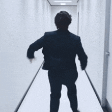 a man in a suit and tie with a name tag around his neck is walking down a hallway