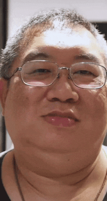 a close up of a man 's face with glasses and a necklace