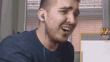 a man wearing blue ear buds is making a funny face in front of a sign that says naruto