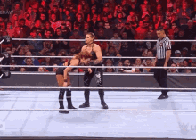 two women are wrestling in a ring with a referee watching