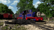 a blue and red train with a smiling face is on a track