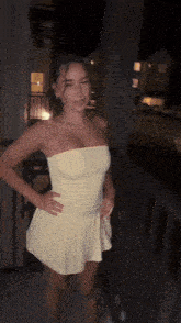 a woman in a strapless yellow dress stands on a balcony