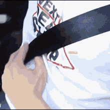 a person wearing a white shirt with the word supreme on it is putting on a seat belt