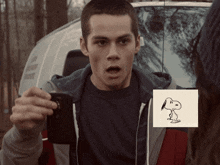 a man is taking a picture of a snoopy drawing on a piece of paper