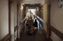 a person pushing another person in a wheelchair down a hallway