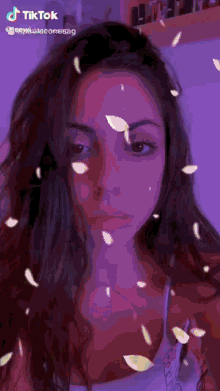 a woman 's face is surrounded by purple petals and a tiktok logo