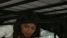 a woman is laying under a bed with a bag that says goddess