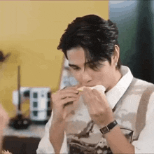 a man is eating a sandwich while wearing a watch and a vest .