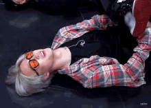 a person wearing sunglasses and a plaid shirt is laying down
