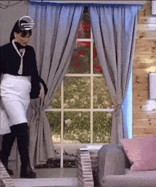a woman in a white skirt and black boots is standing in front of a window