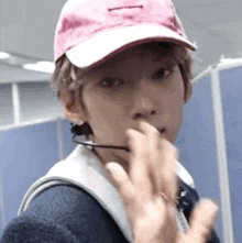 a young man wearing a pink hat and glasses is making a funny face .