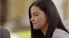a woman with long black hair is looking down at something