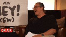 a man sits in front of a sign that says aew on it