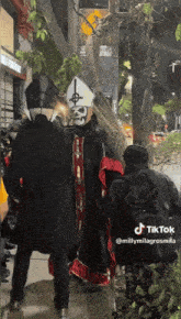 a man dressed as a pope with a cross on his hat is walking down a street
