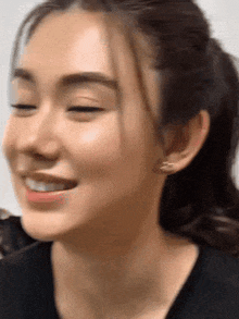 a close up of a woman 's face with her eyes closed and a ponytail .